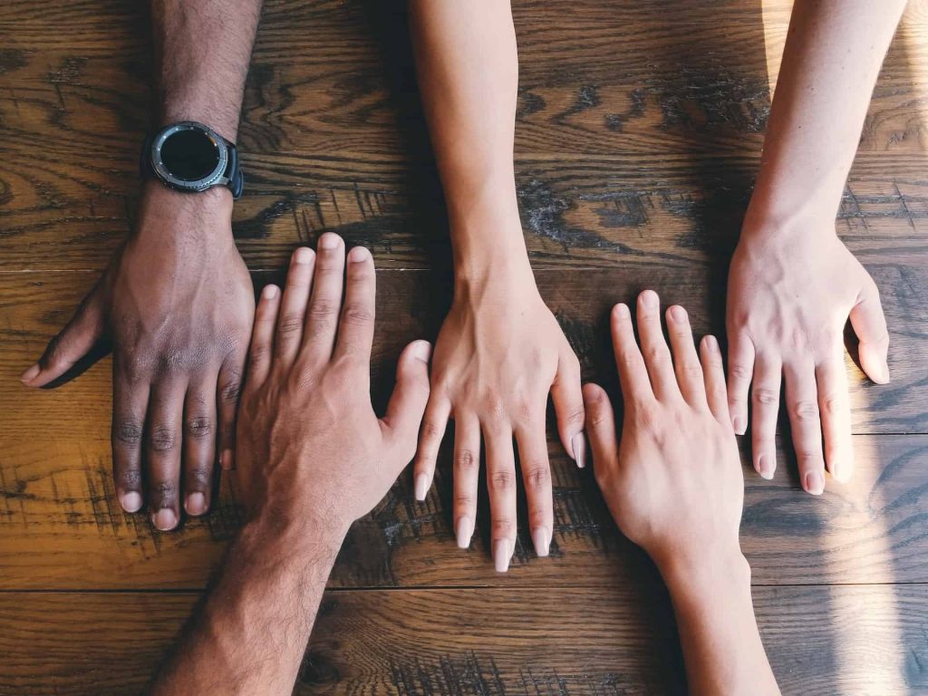 efficiency hub btms hands of men and women on wooden table forming a connection